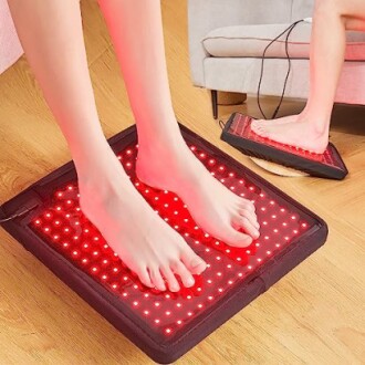 Feet on a red light therapy mat on the floor